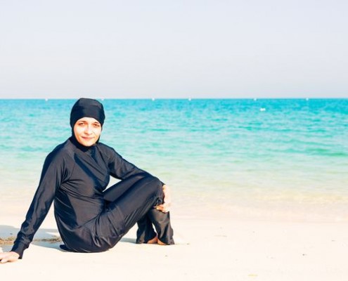 Young-woman-wearing-burkini-sitting-by-the-beach-in-dubai